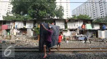 Warga membawa kasur saat alat berat merobohkan bangunan rumah mereka di kawasam Rawajati, Jakarta, Kamis (1/9). Penertiban tersebut menyebabkan warga terpaksa menyelamatkan barang berharga mereka ke tepi rel kereta api. (Liputan6.com/Immanuel Antonius)