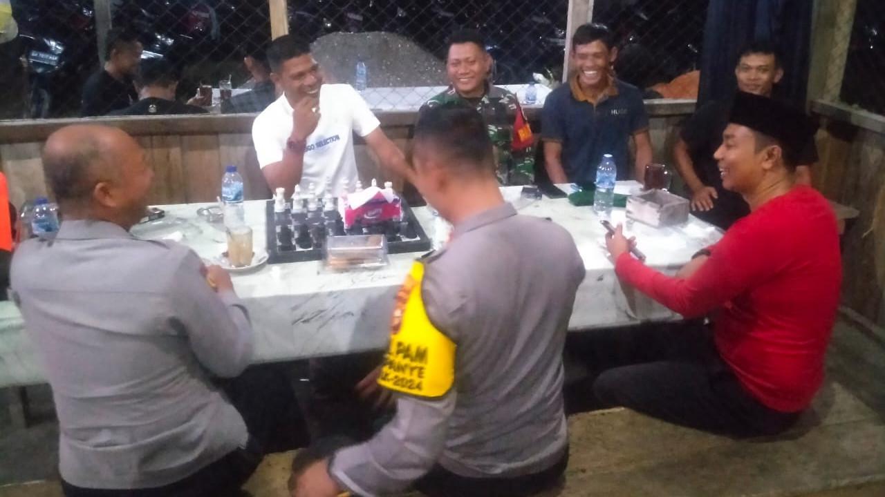 Personel Polres Rokan Hulu duduk santai bersama pedagang pasar di warung kopi.