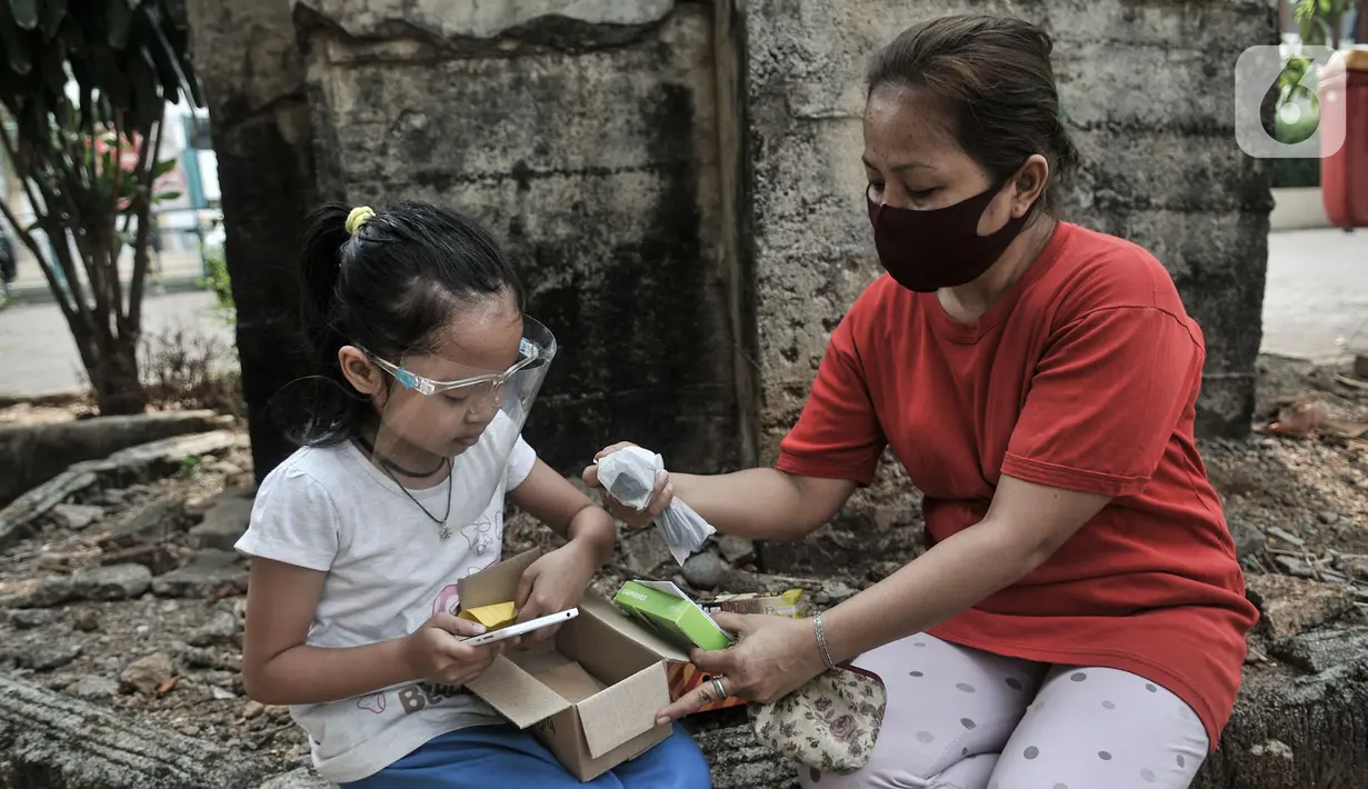 Seorang anak didampingi orang tua saat membuka boks donasi ponsel saat acara #PonselPintarUntukPelajar di Jakarta, Minggu (9/8/2020). Donasi diharapkan dapat membantu mereka dalam mengikuti kegiatan Pelajaran Jarak Jauh (PJJ). (merdeka.com/Iqbal S. Nugroho)