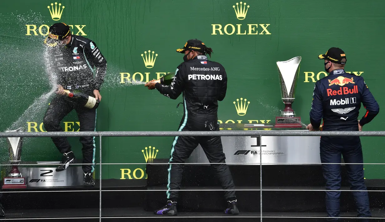 Pembalap Mercedes Lewis Hamilton (tengah) melakukan selebsasi usai menempati posisi pertama Formula 1 Grand Prix di Spa-Francorchamps, Spa, Belgia, Minggu (30/8/2020). Posisi kedua dan ketiga diisi pembalap Mercedes Valtteri Bottas serta pembalap Red Bull Max Verstappen. (John Thys, Pool via AP)