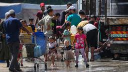 Di kamp Nuseirat, Jalur Gaza Tengah,para pengungsi langsung mengisi wadah mereka ketika bantuan air bersih yang dibawa salah satu truk bantuan tiba. (Eyad BABA/AFP)