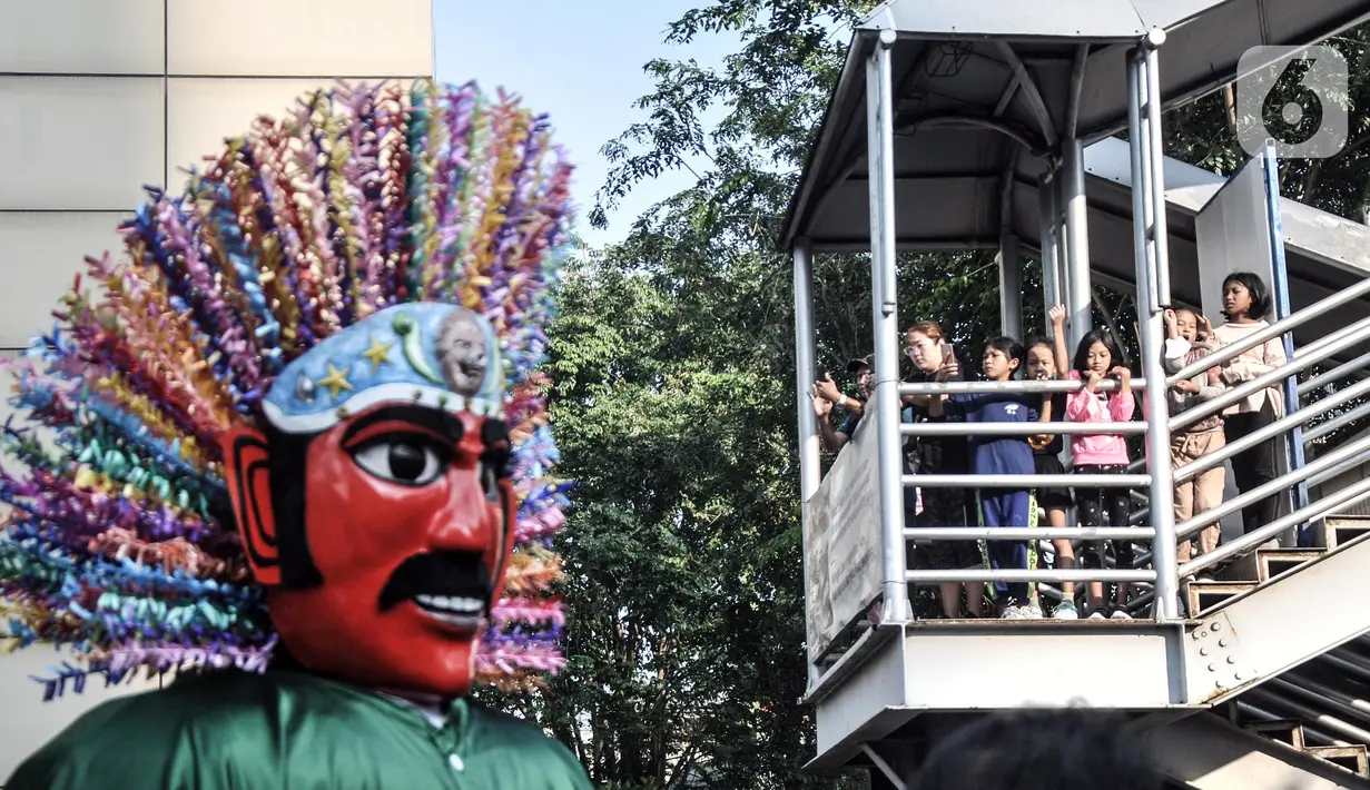 Warga menyaksikan pawai kesenian Betawi saat Hari Bebas Kendaraan Bermotor (HBKB) atau car free day (CFD) di Jalan MH Thamrin, Jakarta, Minggu (19/6/2022). Pawai yang menampilkan berbagai budaya dan kesenian Betawi seperti ondel-ondel, tari topeng, serta tanjidor tersebut digelar dalam rangka menyambut HUT ke-495 DKI Jakarta. (merdeka.com/Iqbal S. Nugroho)