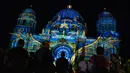 Orang-orang berkumpul di luar Katedral Berlin (Berliner Dom) yang diterangi cahaya dalam Festival of Lights di Berlin pada 14 September 2020. Kreasi cahaya lebih dari 90 karya seni tersebut ditampilkan di 86 lokasi yang berlangsung hingga 20 September mendatang. (John MACDOUGALL/AFP)