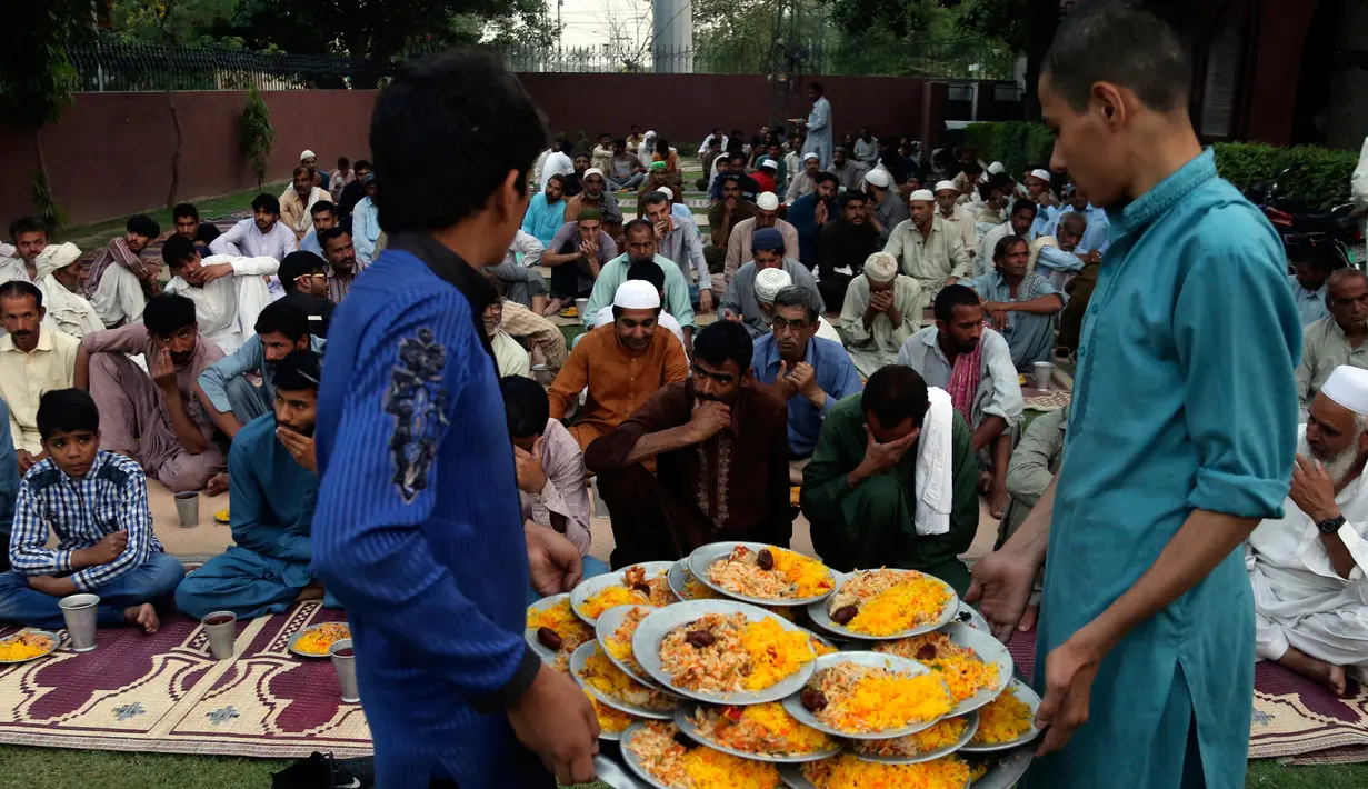 Relawan mendistribusikan makanan berbuka puasa atau iftar kepada muslim Pakistan di sebuah masjid di Lahore pada 7 Mei 2019. Ketika bulan Ramadan mulai di Pakistan, banyak masyarakat muslim memanfaatkan buka puasa gratis yang disponsori oleh badan-badan amal dan orang-orang kaya. (AP/K.M. Chaudary)