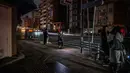 Orang-orang tinggal di sepanjang jalan area perumahan selama pemadaman listrik setelah gempa berkekuatan 7,3 SR mengguncang Jepang timur di distrik Koto di Tokyo (17/3/2022). Gempa kuat Magnitudo 7,3 membuat lebih dari 2 juta rumah di daerah Tokyo menjadi gelap gulita. (AFP/Philip Fong)