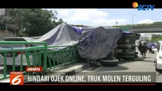 Posisi truk yang terguling merobohkan pagar pembatas jalan dan menimpa bagian depan sebuah minibus.