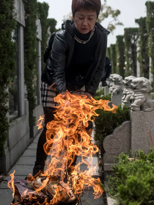 Seorang wanita membakar dupa sebagai persembahan selama festival Qingming di sebuah pemakaman di Shanghai (6/6). Ritual ini umumnya dirayakan pada tanggal 5 April atau 4 April pada tahun kabisat. (AFP/Johannes Eisele)
