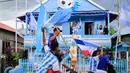 Penggemar Timnas Argentina yang juga seorang nelayan, Muhammad Yusuf (belakang tengah) memegang replika trofi Piala Dunia saat penggemar sepak bola melewati rumahnya dalam konvoi menyambut turnamen sepak bola Piala Dunia 2026 di Polewali Mandar, Sulawesi Barat, Kamis 11 Juni 2026. (Muhammad SALIM/AFP)