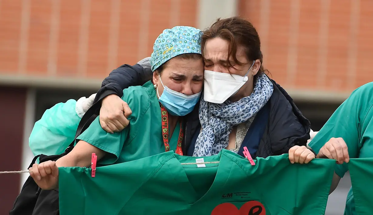 Petugas kesehatan (kiri) menenangkan istri Esteban, perawat yang gugur karena virus corona COVID-19 di Rumah Sakit Severo Ochoa di Leganes, Spanyol, Jumat (10/4/2020). Hingga Minggu (12/4/2020) pagi, total kasus COVID-19 di Spanyol sebanyak 163.027. (Photo by PIERRE-PHILIPPE MARCOU/AFP)