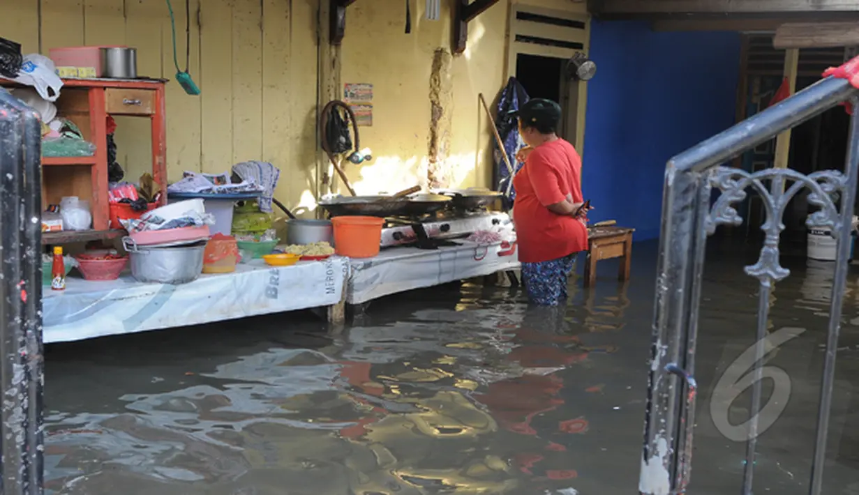 Hujan yang mengguyur Jakarta sejak Minggu (8/2) lalu, membuat Waduk Ria Rio meluap. Meski rumahnya dilanda banjir, ibu ini tetap memasak, Pendongkelan, Jakarta, Selasa (10/2/2015). (Liputan6.com/Herman Zakharia)