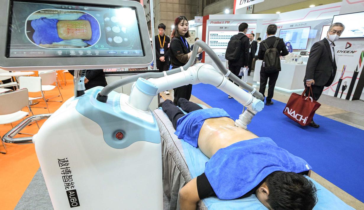 Robot memijat punggung seorang pria di stan AUBO Robotics. (Richard A. Brooks/AFP)