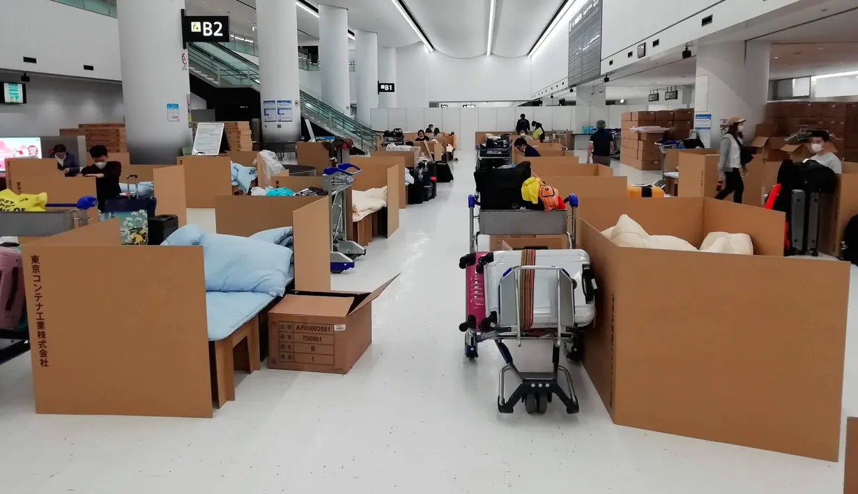 Orang-orang menunggu hasil tes virus corona mereka di tempat tidur sementara dari kotak kardus di Bandara Internasional Narita di Narita, dekat Tokyo, 8 April 2020. Pemerintah Jepang mengharuskan setiap penumpang internasional yang baru saja tiba, untuk menjalani tes corona. (Naohiro Katsuta via AP)