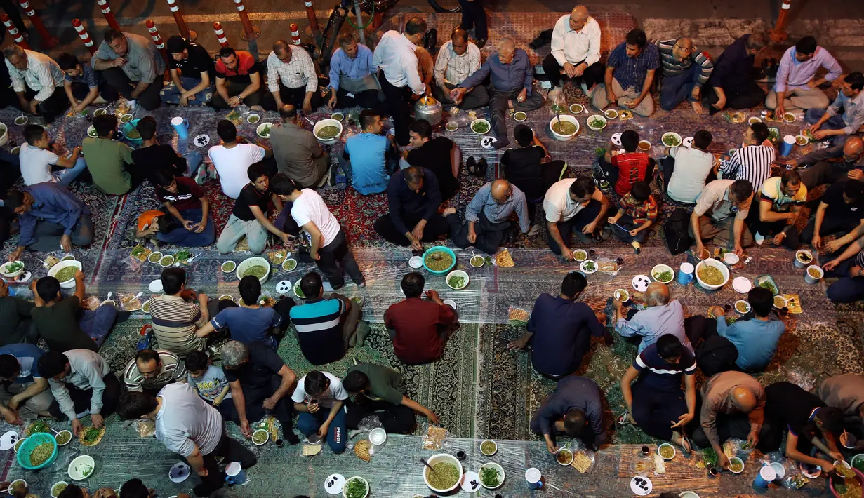 Warga muslim Iran berkumpul untuk berbuka puasa bersama di sebuah jalan di Teheran, 29 Mei 2018. Sebagian besar warga muslim Iran melaksanakan ibadah puasa di bulan Ramadan sesuai ajaran Islam melalui Nabi Muhammad. (AP Photo/Vahid Salemi)