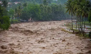 Data Pusat Pengendalian Operasi Penanggulangan Bencana (Pusdalops) BPBD Padang, Kecamatan Koto Tangah menjadi wilayah dengan jumlah terdampak terbesar, yaitu 20.983 warga. Tampak dalam foto, warga bertahan di tepi sungai saat banjir melanda Padang, Provinsi Sumatra Barat, pada Kamis 27 November 2025. (REZAN SOLEH/AFP)