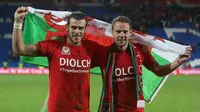 Pemain andalan tim nasional Wales, Gareth Bale (kiri) bersama rekannya Chris Gunter (kanan), merayakan keberhasilan lolos ke Piala Eropa pada 13 Oktober 2015. (AFP PHOTO / Geoff Caddick)