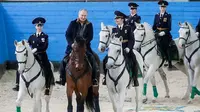Vladimir Putin mengendarai kuda di dalam fasilitas pelatihan di Moskow, Rusia, dengan diapit oleh para polisi wanita dari Resimen Polisi Operasional Pertama (1st Operational Police Regiment) pada hari Kamis, 7 Maret 2019. (Mikhail Metzel/TASS)