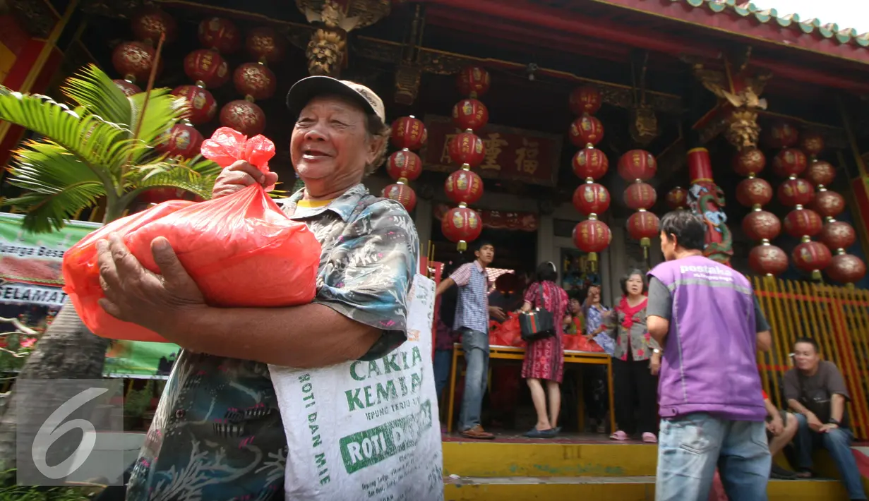 Seorang warga membawa sembako yang di bagikan oleh warga keturunan Tionghoa di Klenteng Fuk Ling Miau, Yogyakarta, Jumat (1/7). Pembagian sembako dilakukan sebagai bentuk kepedulian terhadap sesama di bulan ramadan. (Liputan6.com/Boy Harjanto)