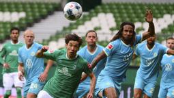 Pemain Werder Bremen, Yuya Osako, berebut bola dengan pemain Wolfsburg, Kevin Mbabu, pada laga Bundesliga di Weserstadion Minggu (7/6/2020). Werder Bremen takluk 0-1 dari Wolfsburg. (AFP/Patrik Stollarz)