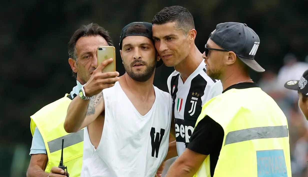 Seorang suporter Juventus berselfie dengan Cristiano Ronaldo selama pertandingan persahabatan antara Juventus A dan tim B, di Villar Perosa, Italia utara, (12/8). Suporter tersebut masuk ke lapangan pada babak pertama. (AP Photo/Antonio Calanni)