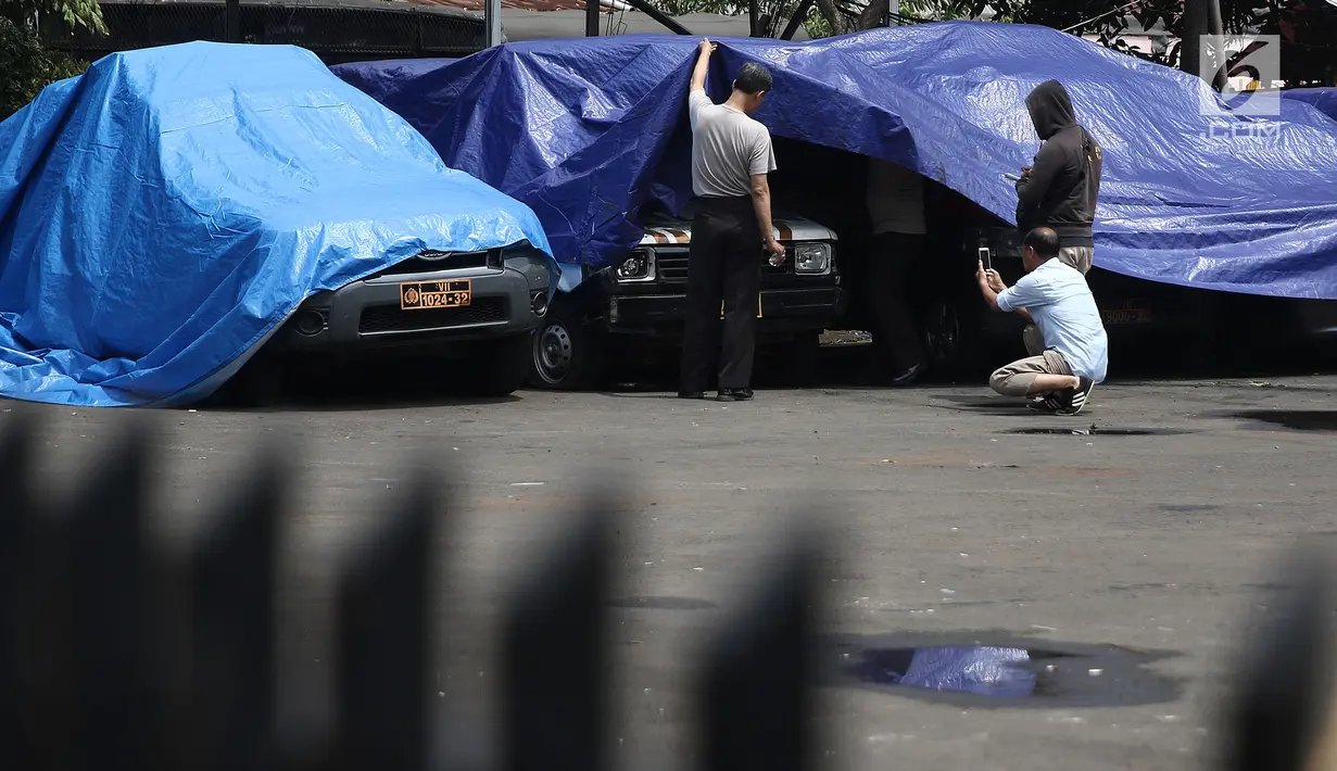 Petugas melihat melihat kondisi mobil yang dirusak di Polsek Ciracas, Jakarta, Rabu (12/12). Polsek Ciracas diamuk oleh sekelompok orang tak dikenal dini hari tadi. (Liputan6.com/Herman Zakharia)