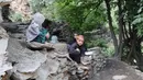 Anak-anak duduk di atas bebatuan setelah banjir bandang menghantam wilayah Ursoon, daerah terpencil Chitral di Pakistan utara, Minggu (3/7). Banjir bandang akibat hujan lebat yang lama itu telah menewaskan sedikitnya 43 orang. (GUL HAMAAD Farooqi/AFP)