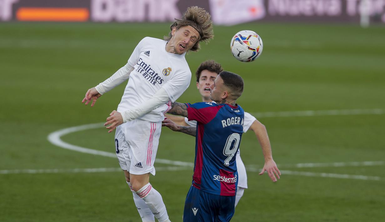 Luka Modric menyundul bola dibayangi pemain Levante. Madrid menyerang, tapi tampak rapuh setiap kali Levante menyerang balik. (Foto: AP/Manu Fernandez)
