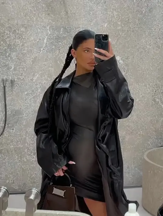 Dengan caption "date night," Kylie Jenner mengunggah foto selfienya dengan outfit serba hitam. Mini dress hitam, ditumpuknya dengan long coat kulit berwarna hitam. Ia juga mengepang rambutnya. Foto: Instagram.