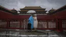 Pengunjung yang ditutupi jas hujan dan payung berdiri di gerbang masuk Kota Terlarang yang tertutup saat hujan badai membasahi Beijing, China, Minggu (30/7/2023). (AP Photo/Andy Wong)