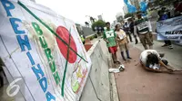 Massa melakukan aksi treatikal berunjuk rasa di depan Kedutaan Besar Jepang, Jakarta, Selasa (9/2). Mereka menuntut penyelesaian kasus PHK 1.300 buruh PT Panarub Dwikarya yang membuat sepatu Adidas dan Mizuno pada 2012 silam. (Liputan6.com/Faizal Fanani)