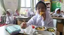 Seorang siswi sekolah dasar sedang menikmati menu makan bergizi gratis di Sekolah Dasar Negeri 01&02, Susukan, Jakarta, Senin (6/1/2025). (Liputan6.com/Herman Zakharia)