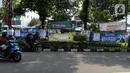 Pengendara motor saat berhenti di samping Alat Peraga Kampanye (APK) yang terpasang di taman kawasan Paseban, Jakarta, Kamis (7/12/2023). (Liputan6.com/Herman Zakharia)