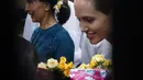 Angelina Jolie dalam kunjungan kemanusiaannya sebagai duta UNHCR terlihat bersama pemimpin oposisi Myanmar, Aung San Suu Kyi, menerima bunga dari pekerja pabrik di asrama perempuan kota HlaingTharYar di Yangon, Myanmar, (1/8/2015). (Bintang/EPA)