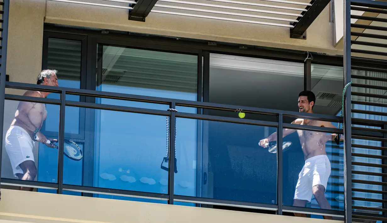 Petenis pria peringkat satu dunia, Novak Djokovic melakukan latihan di balkon hotel, Adelaide, Australia, Rabu (20/1/2021). (Foto: AFP/Morgan Sette)