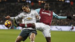 Striker Manchester United, Zlatan Ibrahimovic, berebut bola dengan gelandang West Ham, Pedro Obiang. Meski bermain tandang, MU lebih menguasai bola dengan prosentase penguasaan bola mencapai 64 persen. (AFP/Adrian Dennis)