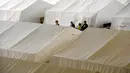 Orang berkumpul di dekat tenda yang didirikan bagi para migran di dalam hanggar bekas bandara Tempelhof di Berlin, Jerman, Rabu (9/12/2015). Jerman menerima satu juta migran dari beberapa negara yang sedang dilanda perang. (REUTERS/Fabrizio Bensch)