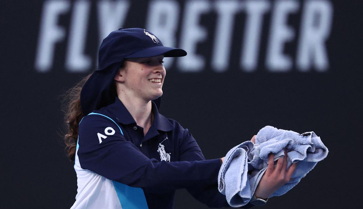 Seorang ball girl menangkap seekor serangga yang memasuki lapangan ketika laga Australia Open 2024 antara petenis Inggris, Emma Raducanu melawan petenis Amerika Serikat di Melbourne Park, Melbourne, Australia, Selasa (16/01/2024). (AFP/David Gray)