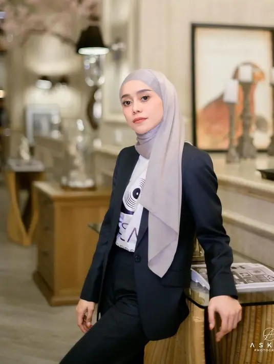 Lesti Kejora mengenakan blazer hitam senada dengan celana panjangnya. Dipadukan inner t shirt putih dan kerudung panjang abu-abu. [@lestikejora]