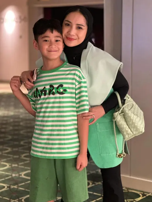 Pose berdua dengan anak sulungnya, Nagita Slavina tampil cantik mengenakan manset dan celana panjang hitam yang ditumpuknya dengan outer bernuansa kehijauan. Ia menutupi kepalanya dengan hijab yang juga berwarna hitam polos. [Foto: Instagram/raffinagita1717]