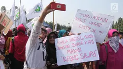 Sejumlah ibu-ibu dari Barisan Emak-Emak Militan Indonesia berswafoto saat menggelar aksi di seberang Istana Merdeka, Jakarta, Rabu (18/7). Massa juga membawa berbagai tulisan berisi tuntutan untuk menurunkan harga bahan pokok. (Liputan6.com/Arya Manggala)