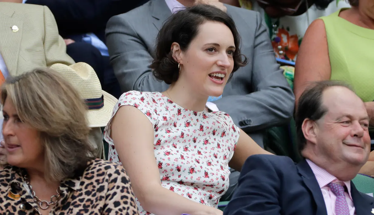 Aktris dan penulis Phoebe Waller-Bridge duduk tersenyum sebelum menyaksikan hari kelima Kejuaraan Tenis Wimbledon 2019 di Royal Box di Centre Court di London (5/7/2019). (AP Photo/Ben Curtis)