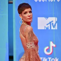 Mantan kekasih G-Eazy ini menggunakan  dress bewarna krem pada acara MTV Awards pada tahun 2018. Meskipun potongan rambutntya pendek, Halsey tetap terlihat anggun dengan tambahan aksesoris antingnya. (Kapanlagi/AFP)