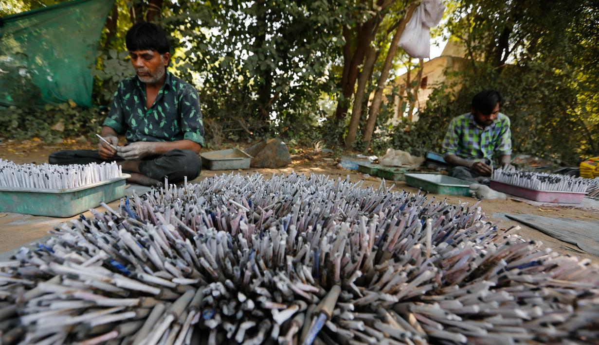 Pekerja membuat petasan untuk festival Diwali atau Dipavali bagi umat Hindu yang akan datang, di sebuah pabrik pinggiran  Ahmadabad, Senin (22/10). Permintaan petasan di India semakin meningkat jelang perayaan Festival "Cahaya" Diwali. (AP/Ajit Solanki)