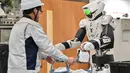 Robot menerima pemberian ember dari seorang karyawan. (Richard A. Brooks/AFP)