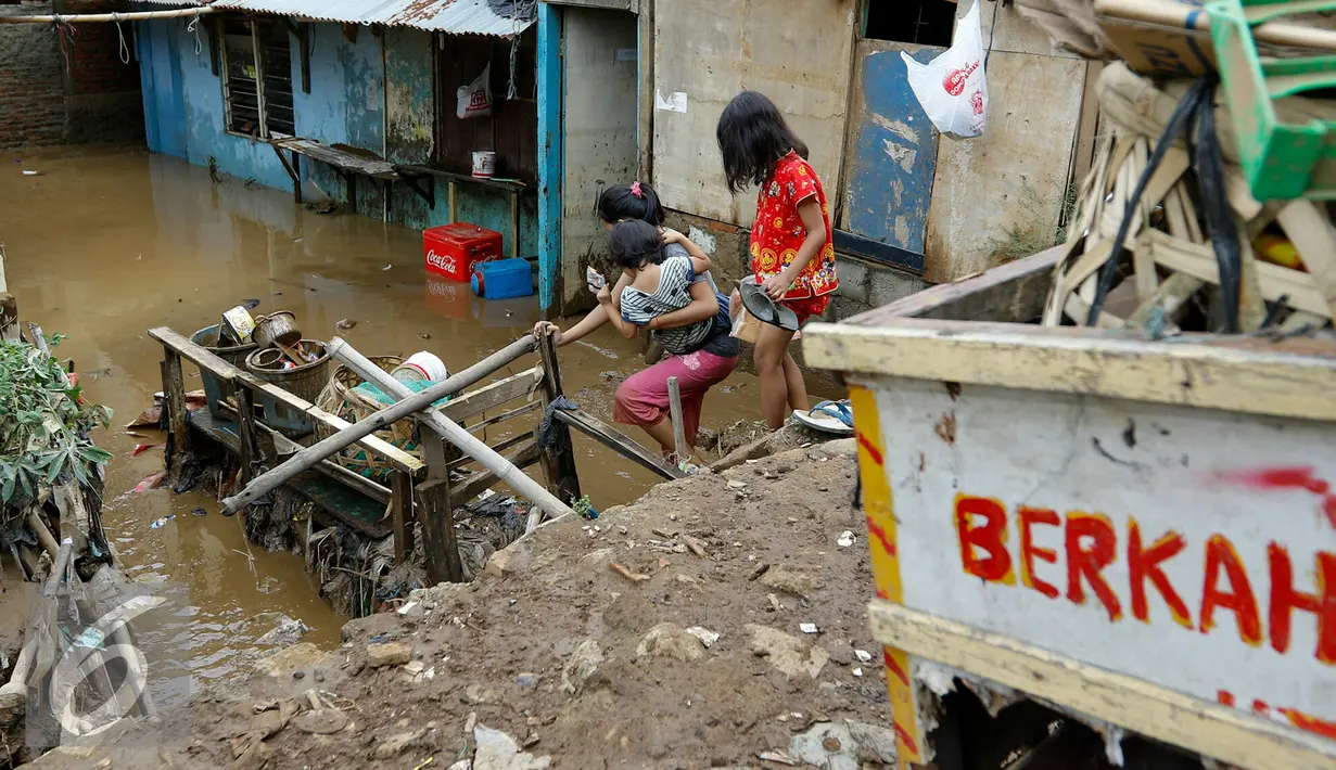 Warga melintasi banjir yang mulai memasuki belasan rumah warga di RT 11/ RW 07 sejak pukul 01.00 WIB dini hari tadi, Jakarta, Senin (16/11/2015). Ketinggian air mencapai 3 meter saat subuh dan merendam puluhan rumah. (Liputan6.com/Yoppy Renato)