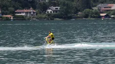 Seorang warga beraksi dengan sepeda air pada di d'Annnecy (Annecy lake) pada etape ke-9 Tour De France dengan jarak tempuh 146km, antara Albertville dan Saint-Gervais Mont Blanc, Prancis (22/7/2016). (AFP/Kenzo Tribouillard)