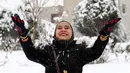 Seorang wanita melempar salju di Teheran, Selasa (24/1). Hampir setengah abad salju tak turun di Iran dan sejak 2011 hingga kini salju senantiasa turun di musim dingin. (AFP PHOTO / ATTA KENARE)   