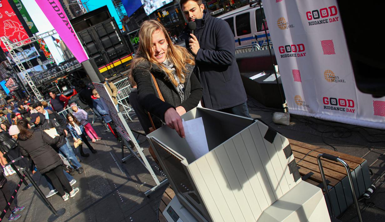 Seorang perempuan menghancurkan kertas berisi kenangan pahit selama kegiatan Good Riddance Day ke-13 tahunan di Times Square, New York, 28 Desember 2019. Kegiatan menjelang tahun baru tersebut menjadi tradisi untuk menghapus kenangan buruk selama satu tahun. (Kena Betancur / AFP)