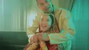 Raffi Ahmad mengenakan pakaian sherwani khas Pria India. Sherwani Raffi memiliki warna keemasan dengan bordiran pada bagian depan dan kerah. [YouTube Dewa19]