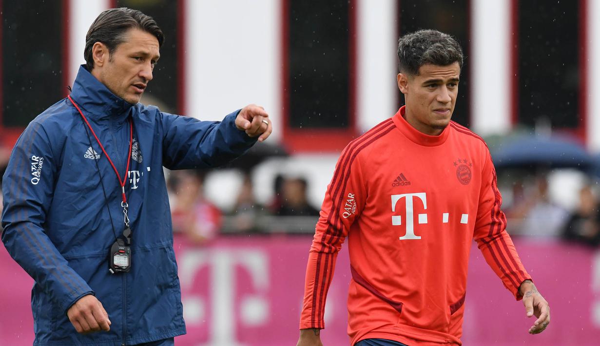 Pemain Bayern Munchen, Philippe Coutinho, mendengarkan instruksi Niko Kovac saat latihan perdananya di Munchen, Selasa (20/8). Bintang Brasil ini didatangkan dari Barcelona. (AFP/Christof Stache)