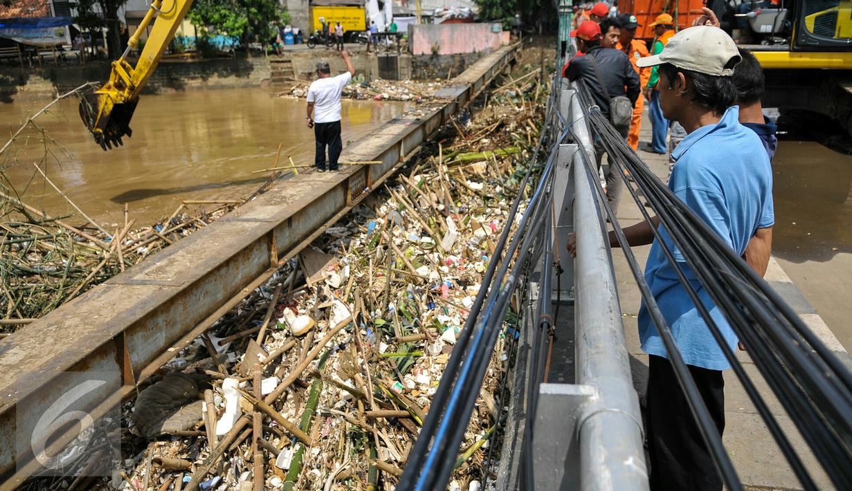 Warga melihat proses pengangkatan sampah dari jembatan Kampung Melayu, Jakarta, Minggu (3/4/2016). Akibat luapan Ciliwung, tumpukan sampah menyangkut di jembatan Kampung Melayu. (Liputan6.com/Yoppy Renato)